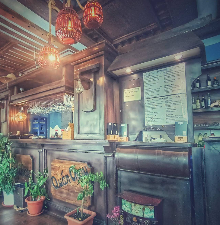 The warm wooden bar at Veganese with the hand-painted Quán Chay sign