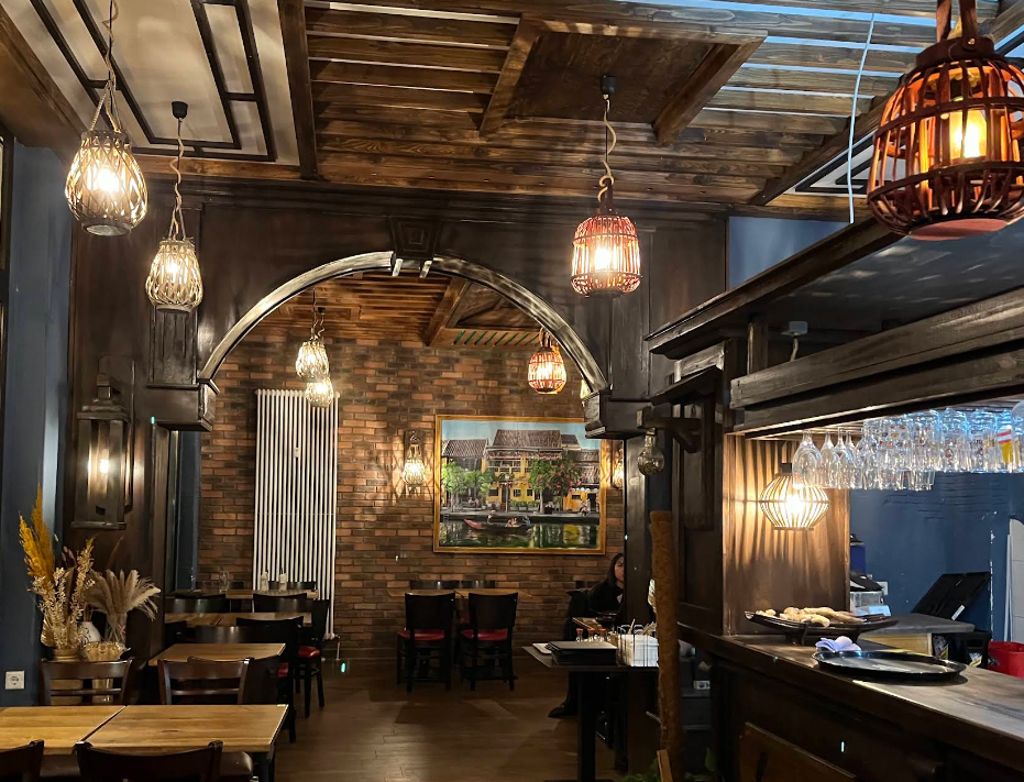 The warm, lantern-lit dining room at Veganese with a painting of Hội An